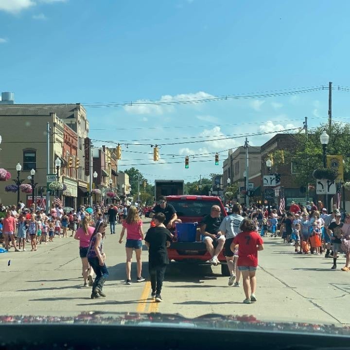 Crowd on the road as kids joyfully chase a car