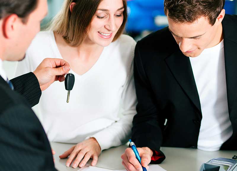 A couple signing a contract with a car dealer